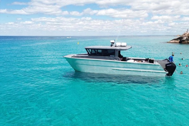 Boat floating on clear turquoise sea under a sunny sky.