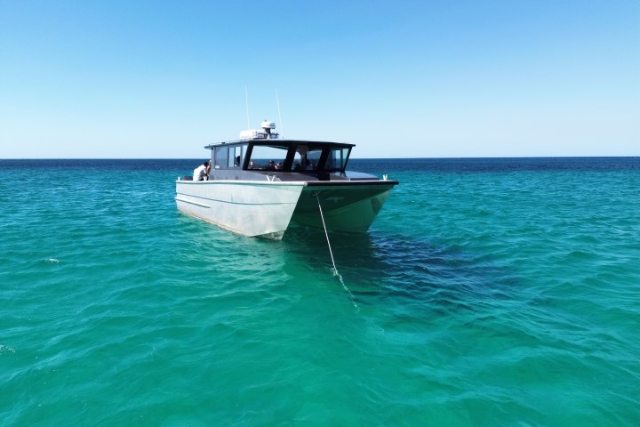 Boat anchored on clear turquoise water under a clear blue sky.