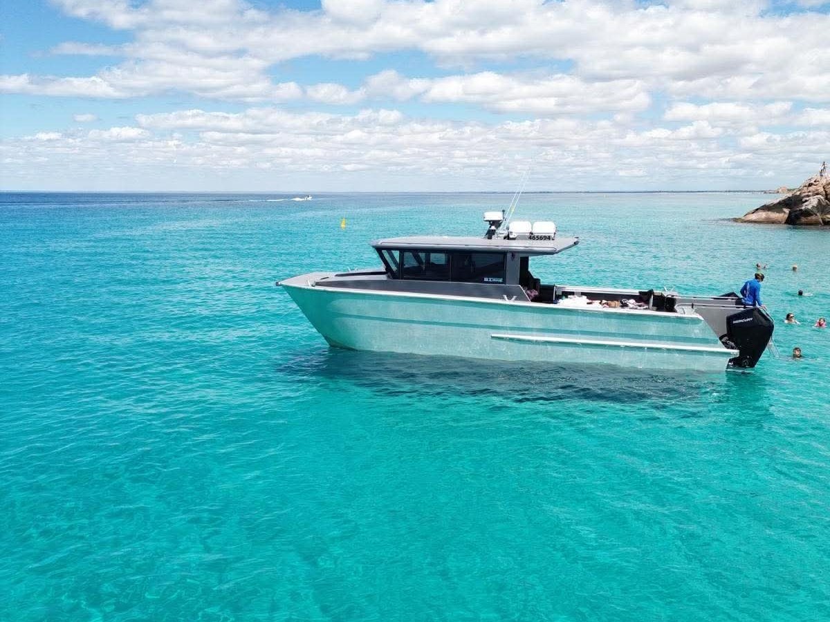 Boat anchored on clear turquoise water under a partly cloudy sky.