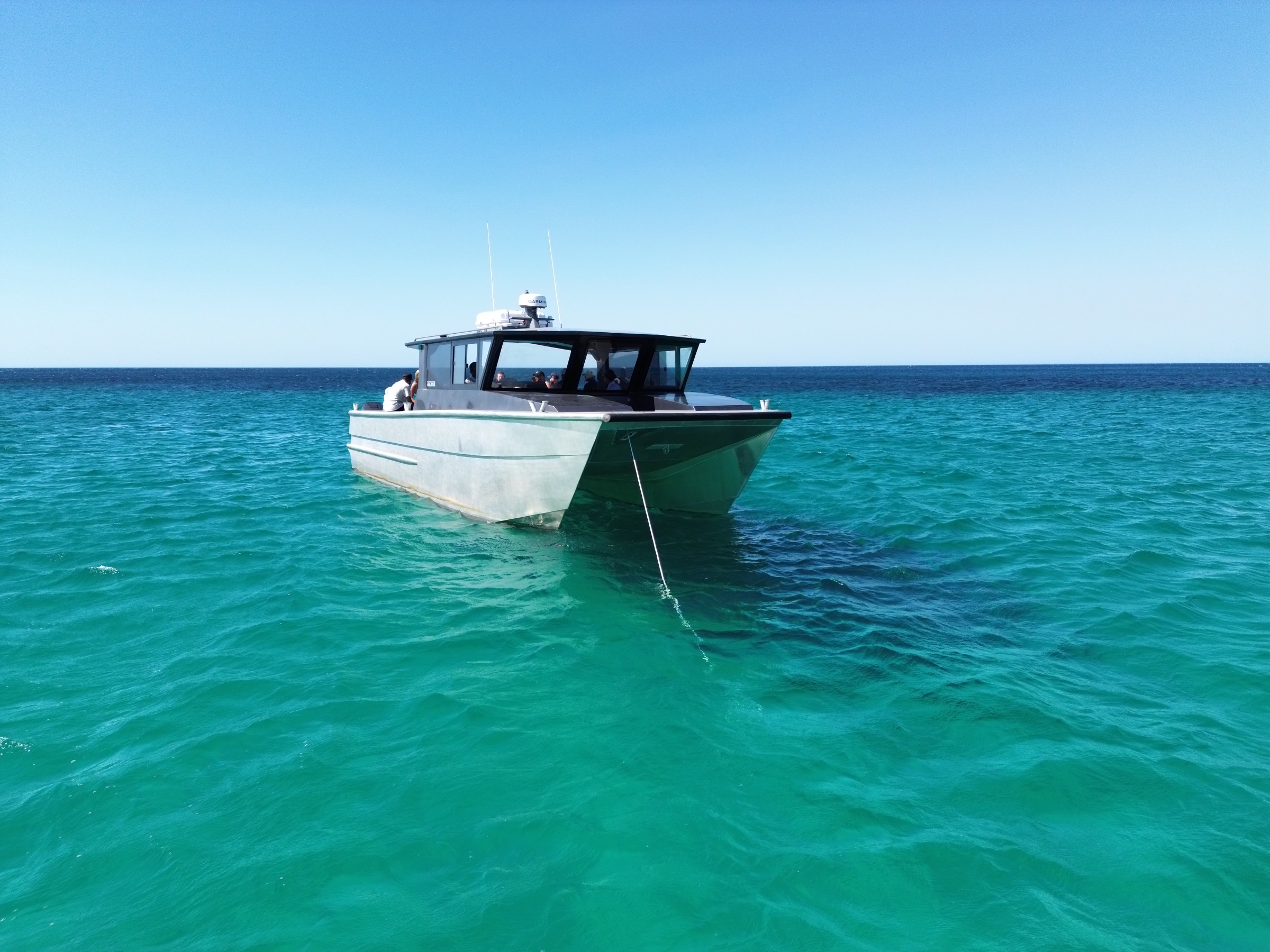 Boat anchored on clear turquoise ocean under a clear blue sky.
